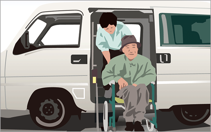 送迎車から職員が車椅子の利用者をおろしている